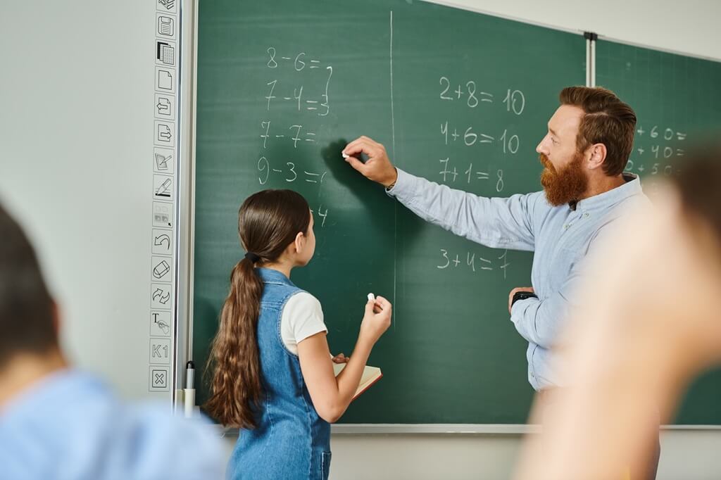 professor de matemática escrevendo na lousa ao lado de aluna