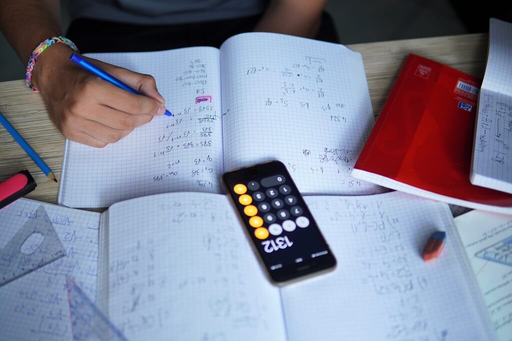 estudante fazendo cálculos de matemática com calculadora à frente