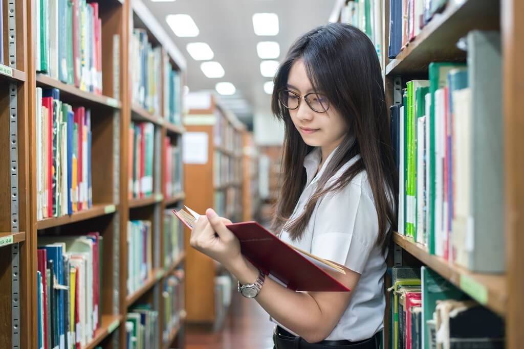 moça lendo livro em biblioteca
