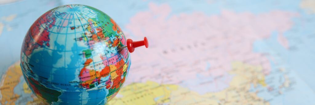 globo terrestre com pin em cima de mapa do mundo
