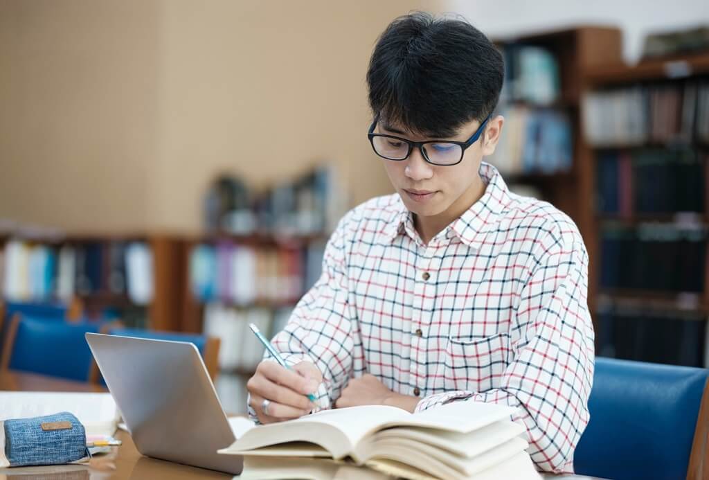 rapaz estudando em biblioteca