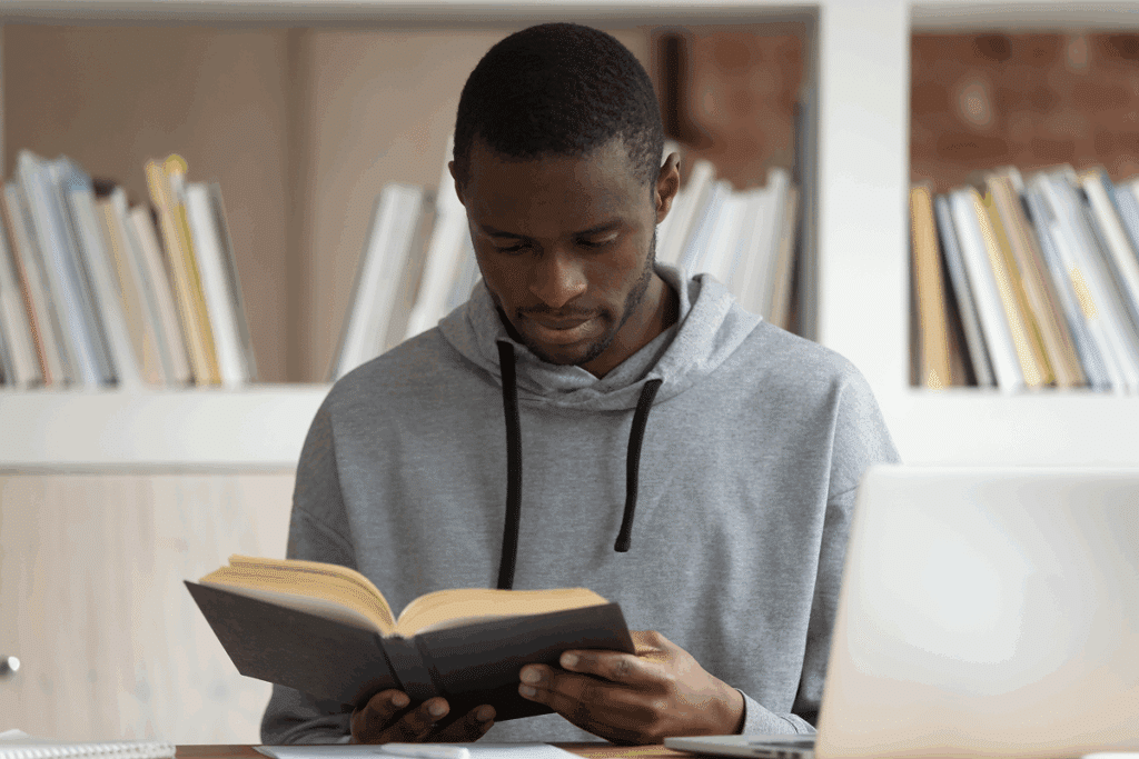 Jovem lendo um livro em biblioteca. Figuras de linguagem